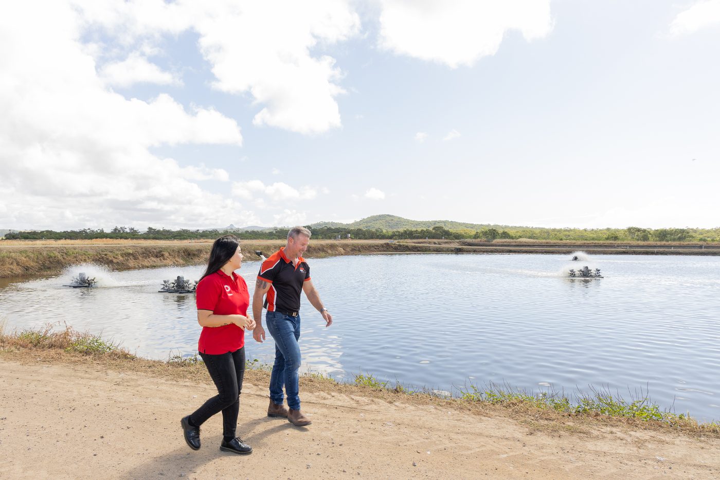 Coles ethical sourcing representative walking with the Australian Prawn Farms operator beside the prawn pond